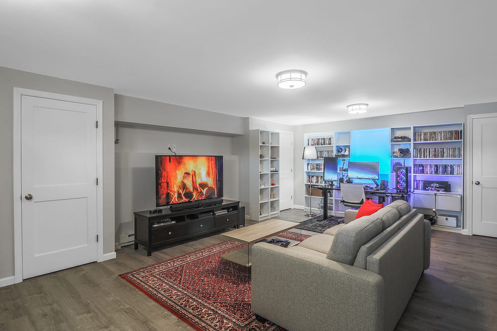 large living room with black entertainment center and desk with pc and 2 monitors by raymond design builders in ct