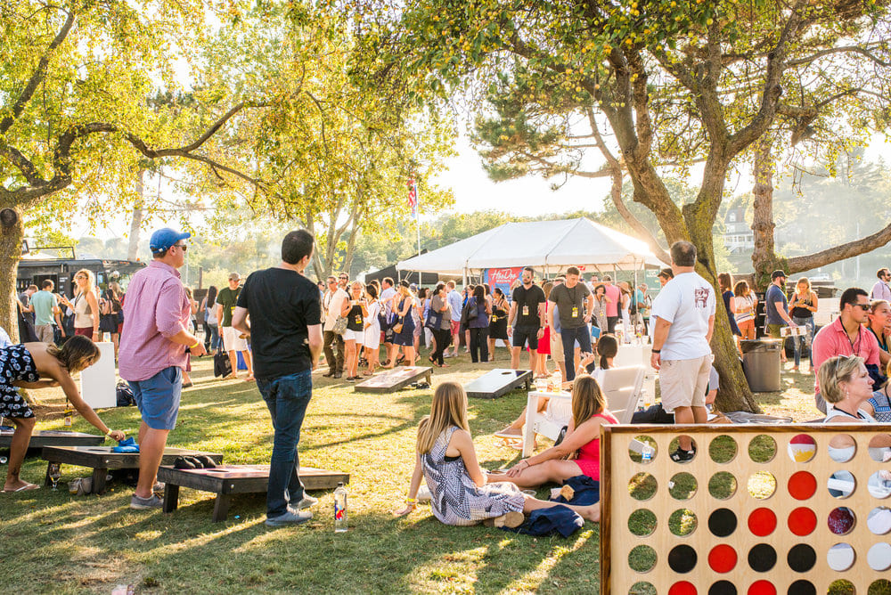 large festival with lawn games in green grass and large white tent in distance - Photo by Manny Vargas