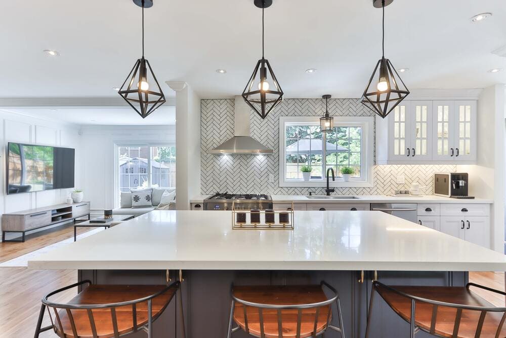 luxury white kitchen with herringbone textured backsplash and black geometric light fixtures